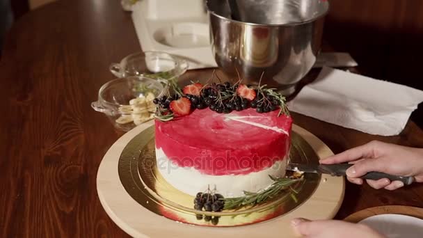 Close up shot of a sweet cake that a woman cuts and puts a slice on a plate — Stock Video