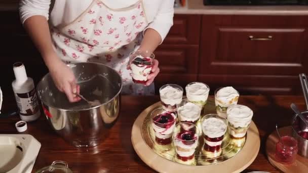 Молодая девушка кладет слой белого крема в десерт — стоковое видео