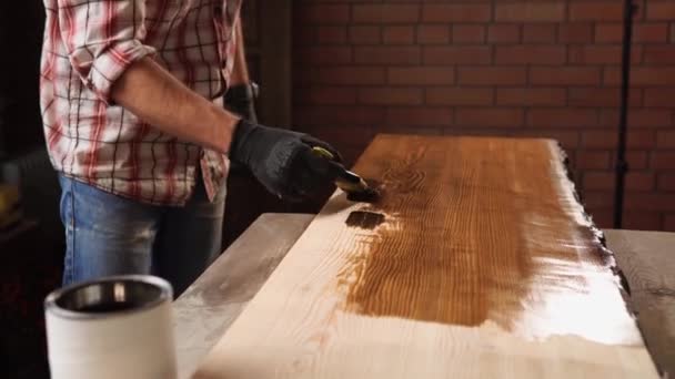 Крупним планом знімок рук чоловіка, який фарбує дерев'яний стіл лаком — стокове відео