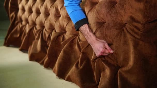 Bliska strzał rąk mistrza, który dostosowuje tkaniny na kanapie, którą stworzył — Wideo stockowe