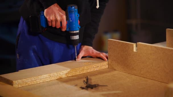 Close up shot of male hands, carpenter uses electric drill in workshop — Stock Video