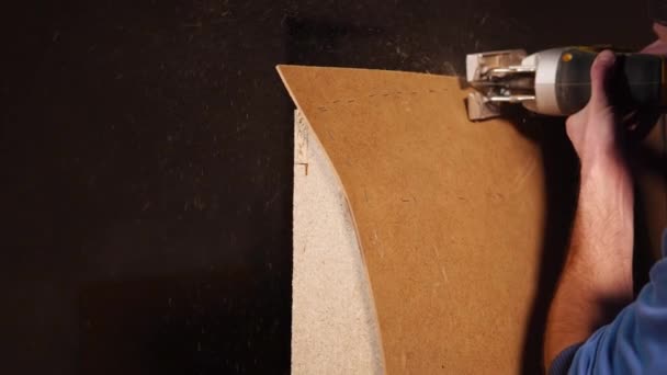 Trabalhador usa serra elétrica em uma madeira compensada — Vídeo de Stock