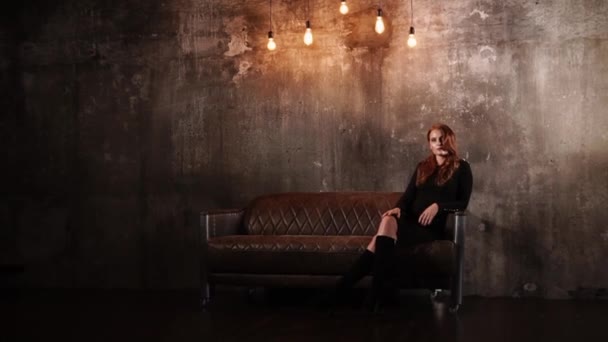 Model is sitting on a leather couch — Stock Video