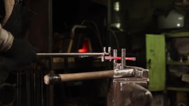 Close up shot of a red hot strip of steel which is bent and beaten with a hammer — Stock Video