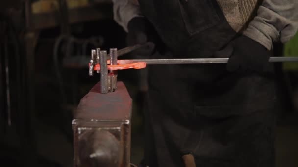 Крупным планом снимок рук человека, который сгибает сталь на наковальне в дуге — стоковое видео