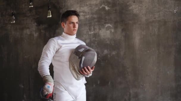 Портрет красивого мужчины с шлемом и спортивным рапиром в руках — стоковое видео