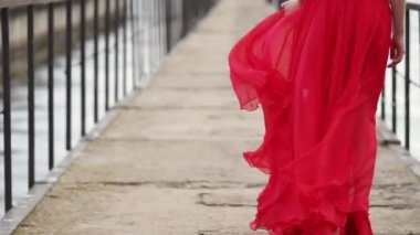 Yalnız güzel kadın onun bacakları ve uzun elbise görünümünü iskele üzerinde geri gidiyor