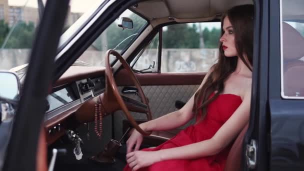Самотня і розчарована красива дівчина знаходиться всередині припаркованої машини з відкритими дверима — стокове відео