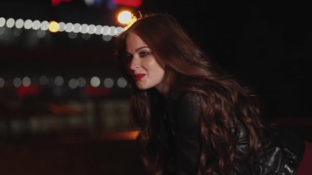 Neşeli Kızıl saçlı kadın gece şehir ışıkları arka plan üzerinde duruyor — Stok video