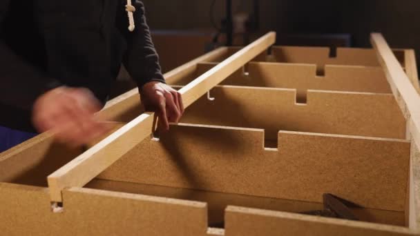 Furniture maker is fixing a wooden beam inside a construction of sofa frame — Stock Video