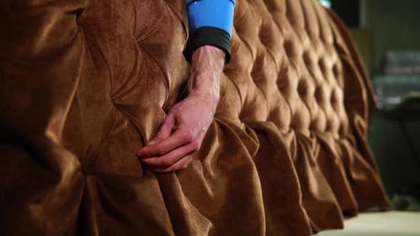 Чоловік випрямляє тканину на дивані в майстерні зі складання меблів — стокове відео