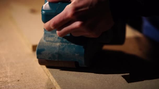 Master sta levigando un pannello di particelle di legno in un laboratorio di mobili con smerigliatrice — Video Stock