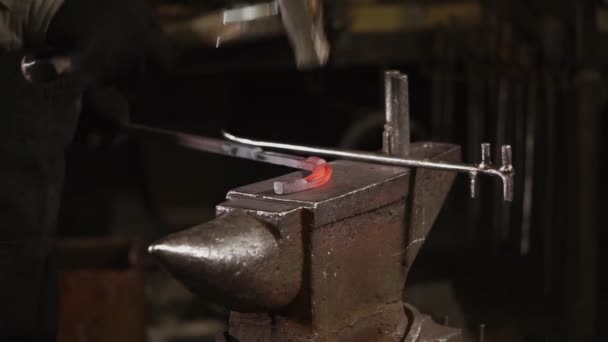 Herrero está golpeando sobre la palanquilla de metal caliente en un yunque en forja — Vídeos de Stock