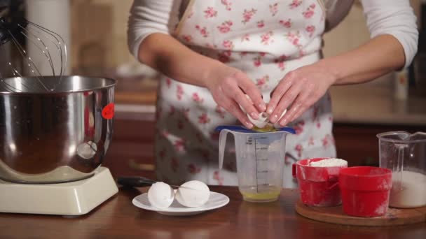 Szakács nő tojás feltörésére és elválasztó fehérek, a sárgáját a konyha — Stock videók