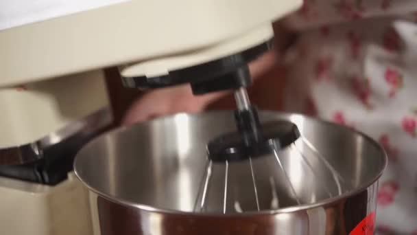 La femme laisse tomber la partie supérieure du mélangeur dans un bol et allume — Video
