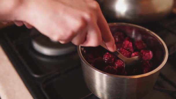 Кондитер готовит сироп с вишней, помешивая в миске на плите — стоковое видео
