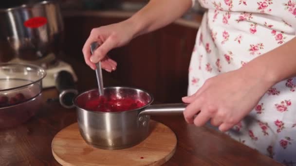 Σεφ ζαχαροπλαστικής μίξη κόκκινων μούρων σάλτσα σε ένα μπολ στο τραπέζι της κουζίνας — Αρχείο Βίντεο