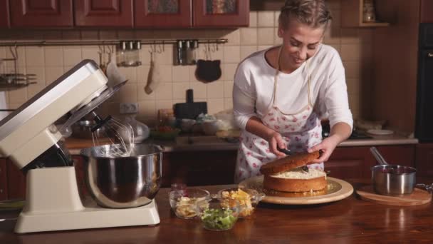 Menina loira jovem está cortando boleto biscoito em camadas para cozinhar bolos — Vídeo de Stock