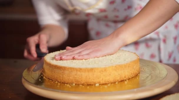 Femme coupe un gâteau rond sur deux couches, tenant sur une table de cuisine — Video