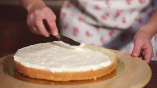 Dona de casa é revestimento de uma camada de bolo por creme branco doce — Vídeo de Stock