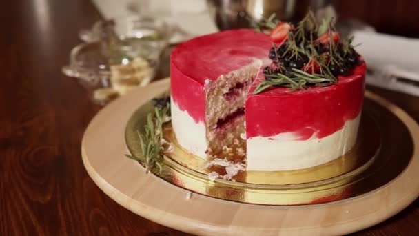 Gelaagde taart is op een tafel, de vrouw s hand corrigeert decoraties — Stockvideo