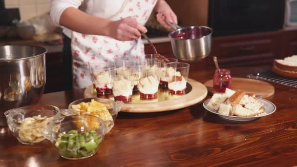 Жінка затоплює фруктовий десерт ягодами рідких мармеладів на кухні — стокове відео