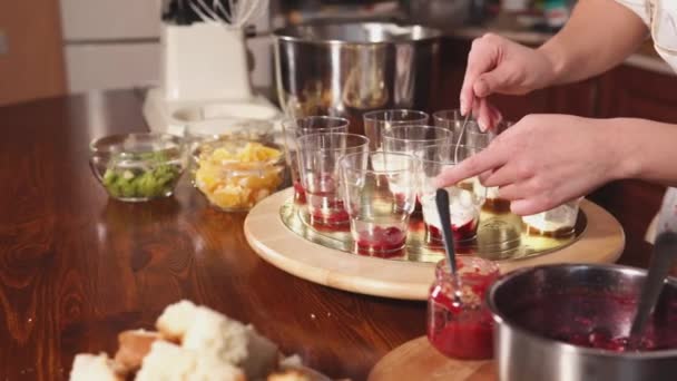 Pastelera mujer chef está extendiendo crema batida en tazas de postre — Vídeos de Stock