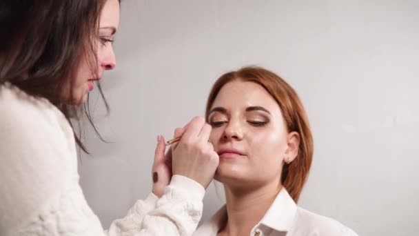 Visagiste está pintando sobre el párpado inferior de la mujer por las sombras — Vídeos de Stock