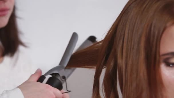 Close-up of curling iron in a hand of hairstylist, making hairdo for woman — Stock Video