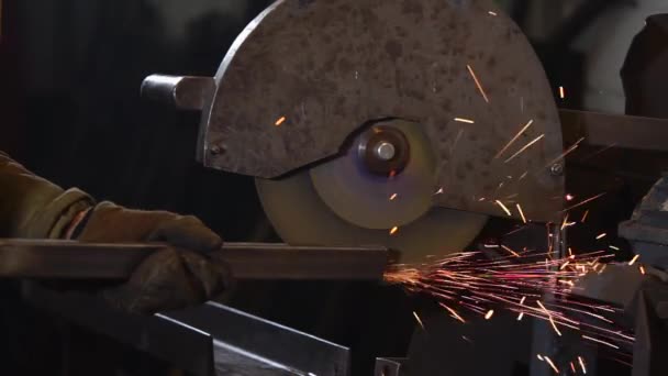 Worker is grinding edge of metal beam by disk of polishing machine in factory — Stock Video