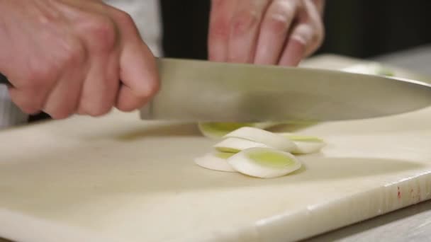 Close up shot of a mans hands, cook cuts a leek on a cutting board, then pepper — Stock Video