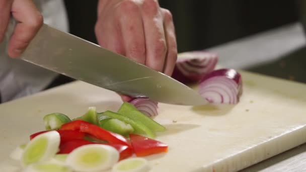 Perto tiro das mãos dos chefs, ele corta uma cebola vermelha em pedaços — Vídeo de Stock