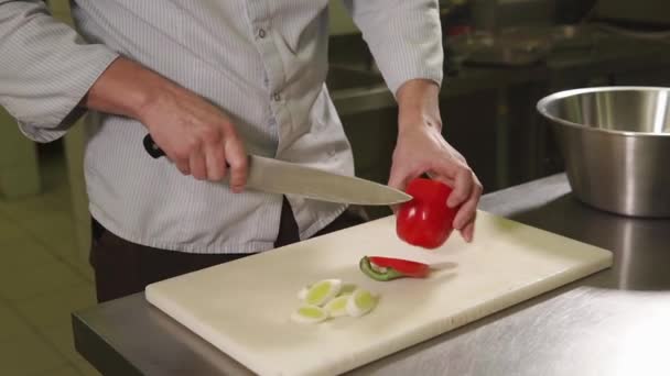 Close up tiro dos chefs mãos o homem tira, corta a pimenta em pedaços — Vídeo de Stock