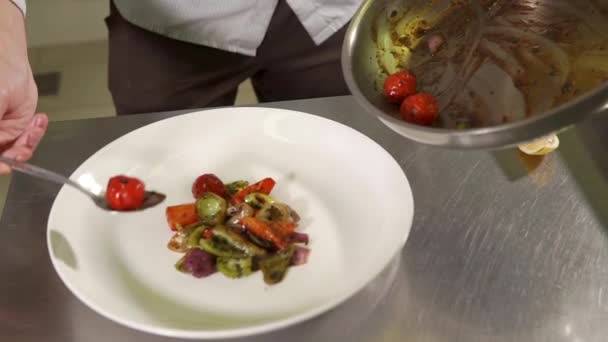 Крупным планом руки человека, повар аккуратно кладет жареные овощи на тарелку — стоковое видео