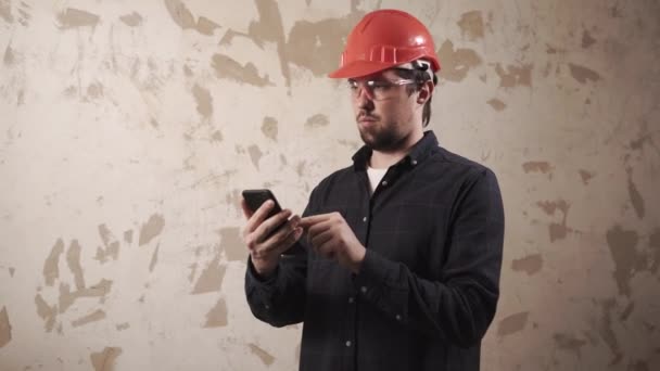 一个男人的肖像, 是在一个建筑工地用智能手机在他的手 — 图库视频影像