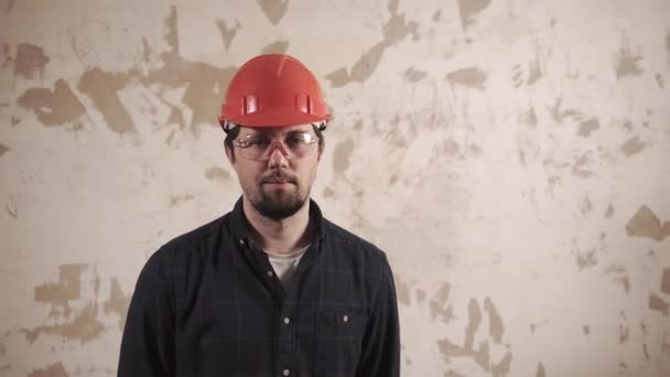 Retrato de un mayordomo, un trabajador se encuentra en el fondo de una pared reparada — Vídeos de Stock