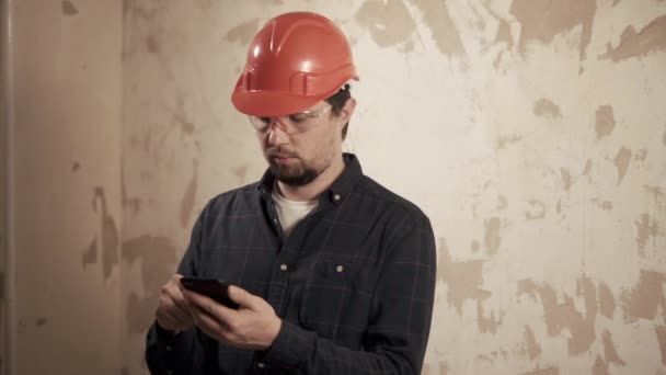 Een portret van een voorman die het voltooide werk op de lijst op de telefoon controleert — Stockvideo