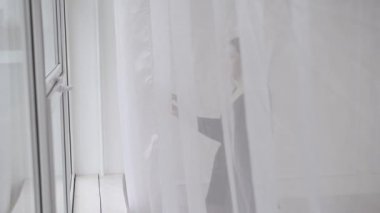 kadın pencerenin yaklaşımlar ve geri perde çeker, mesafe içine benziyor