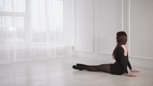Een vrouw in pointe sportschoenen is betrokken bij het opwarmen van de spieren van haar benen — Stockvideo