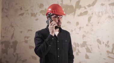 Adam boş odada telefonda konuşuyor.