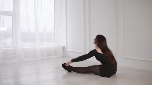Молодая романтичная девушка тренируется в балетном классе с дневным светом из большого окна — стоковое видео
