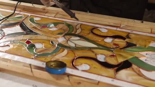 Mestre de vidro manchado está soldando com estanho uma base de cobre para vitrais — Vídeo de Stock