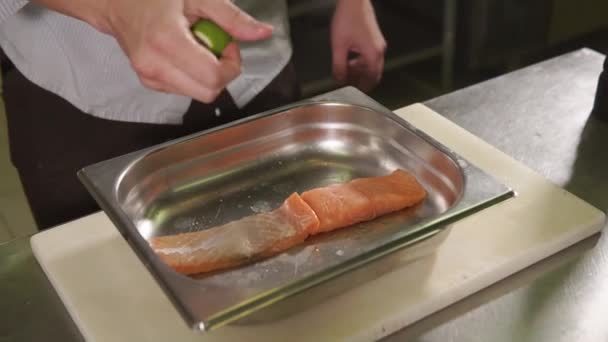 Chef is spluttering fish fillets by juice of lime on a professional kitchen — Stock Video