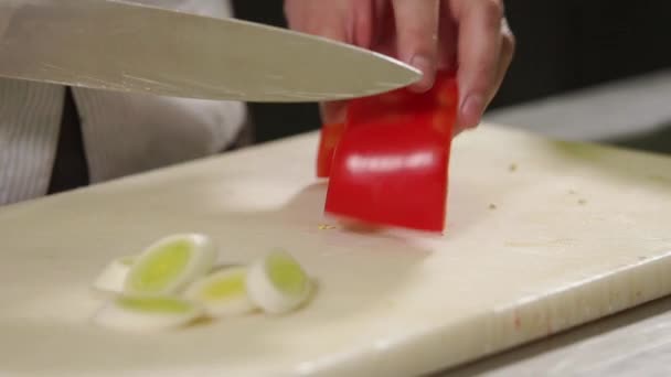 Cook coupe un poivron rouge sur une planche en bois dans une table de cuisine, gros plan — Video