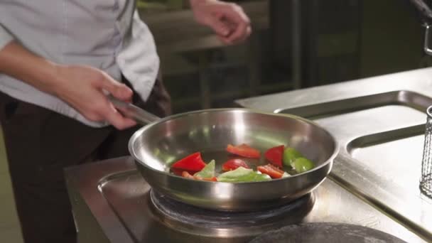 Шеф-кухар кладе нарізану паприку на гарячу сковороду з олією і перетворює її — стокове відео