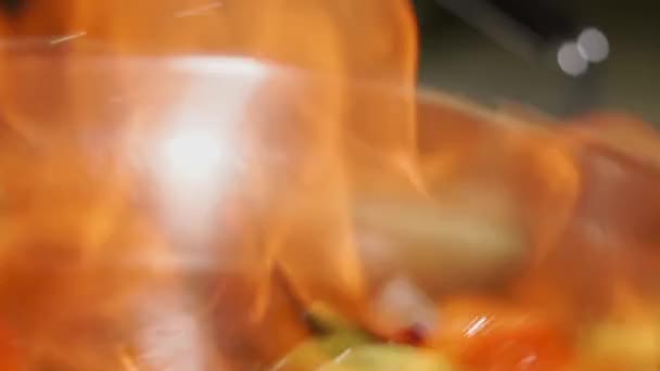 Inflamação de verduras em uma panela de refogue, vista pelo fogo, close-up — Vídeo de Stock