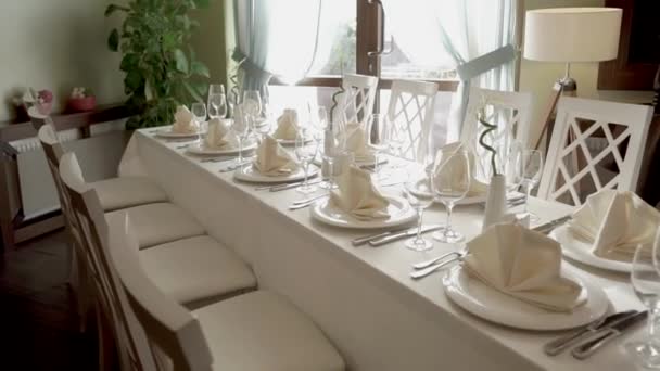 Served table for banquet in a clear light room of small restaurant in daytime — Stock Video