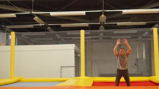 Joven se dedica a acrobacias aéreas en trampolines estirados — Vídeo de stock