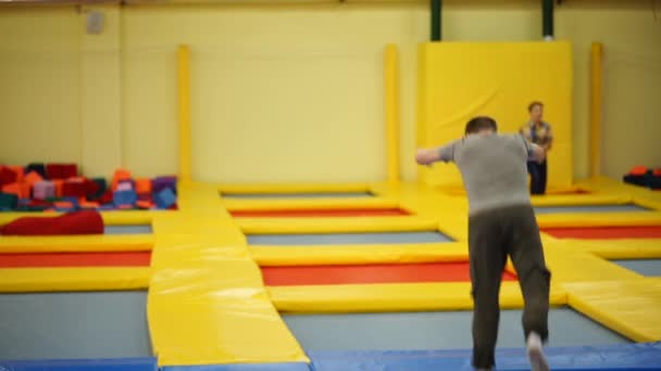 Único acrobata está fazendo uma série de saltos em um trampolim em um salão de esporte — Vídeo de Stock