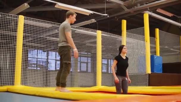 Trainer by trampolining enseigne à une jeune femme à sauter dans une salle de gym — Video